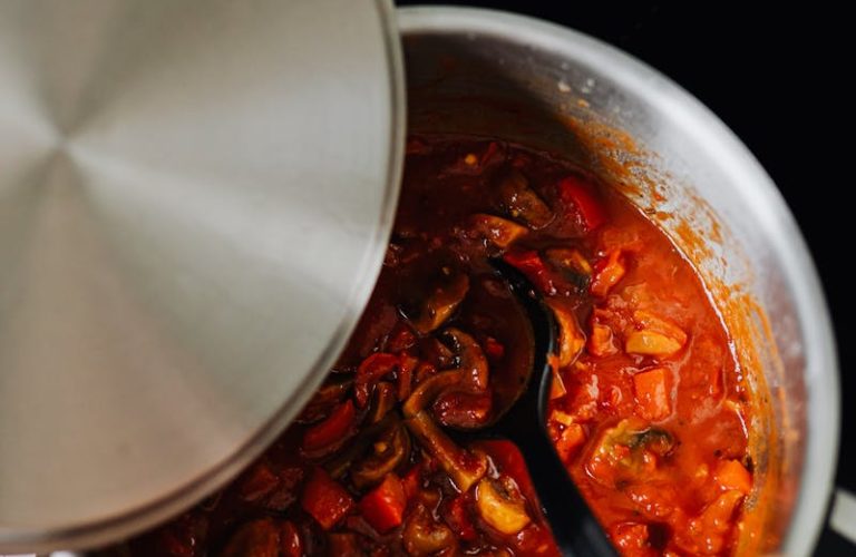 Close-up of shakshuka cooking in pot with spoon stirring. Perfect for culinary enthusiasts.