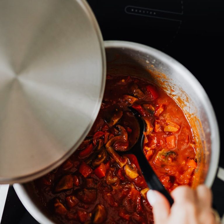 Close-up of shakshuka cooking in pot with spoon stirring. Perfect for culinary enthusiasts.