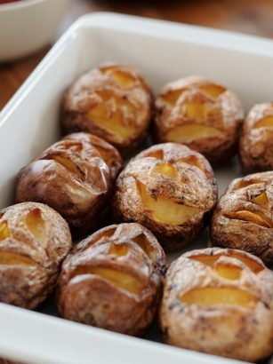 Tray of baked potatoes with carved Halloween faces, perfect for festive meals.
