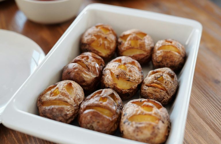Tray of baked potatoes with carved Halloween faces, perfect for festive meals.